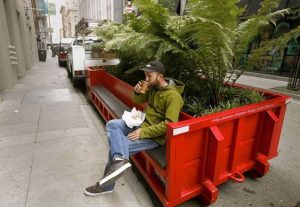 Man sitting on red box city parklet