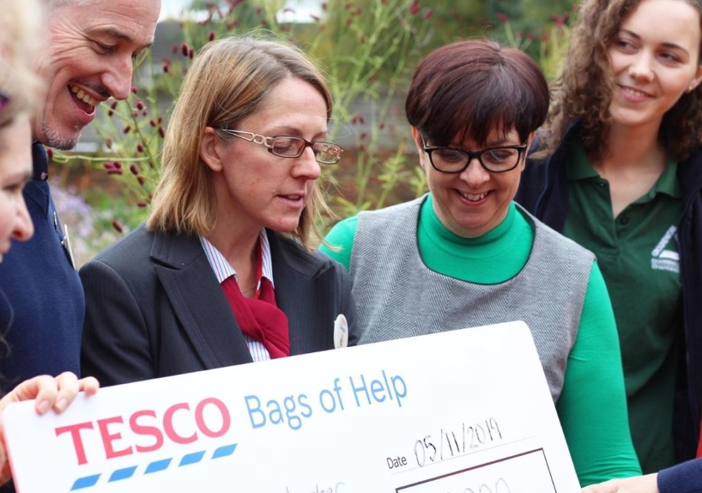 Maggies Manchester receiving a large cheque from Tesco funding in partnership with groundwork