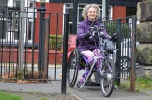 Woman using handcycle smiling as she goes through modified gate