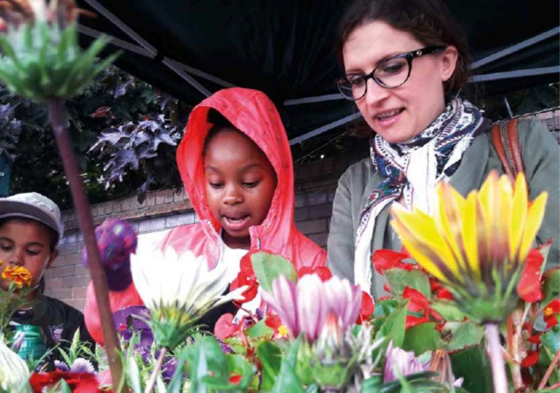 Picture of a woman and children in a park with flowers in foreground