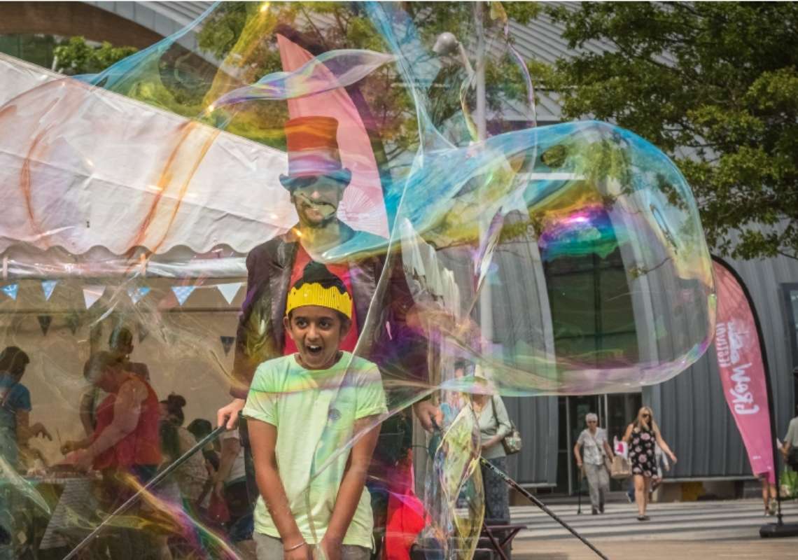 Report cover image: a young boy is entertained by a street performer blowing bubbles