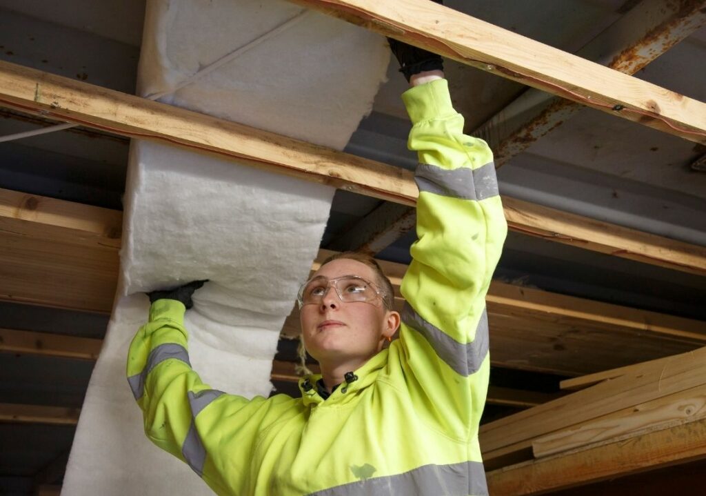 Young person installing insulation to improve energy efficiency