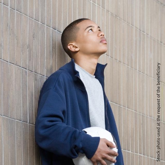 (Stock photo) A teenage boy holding a football and looking up at the ceiling as part of the Achievment Coaching programme