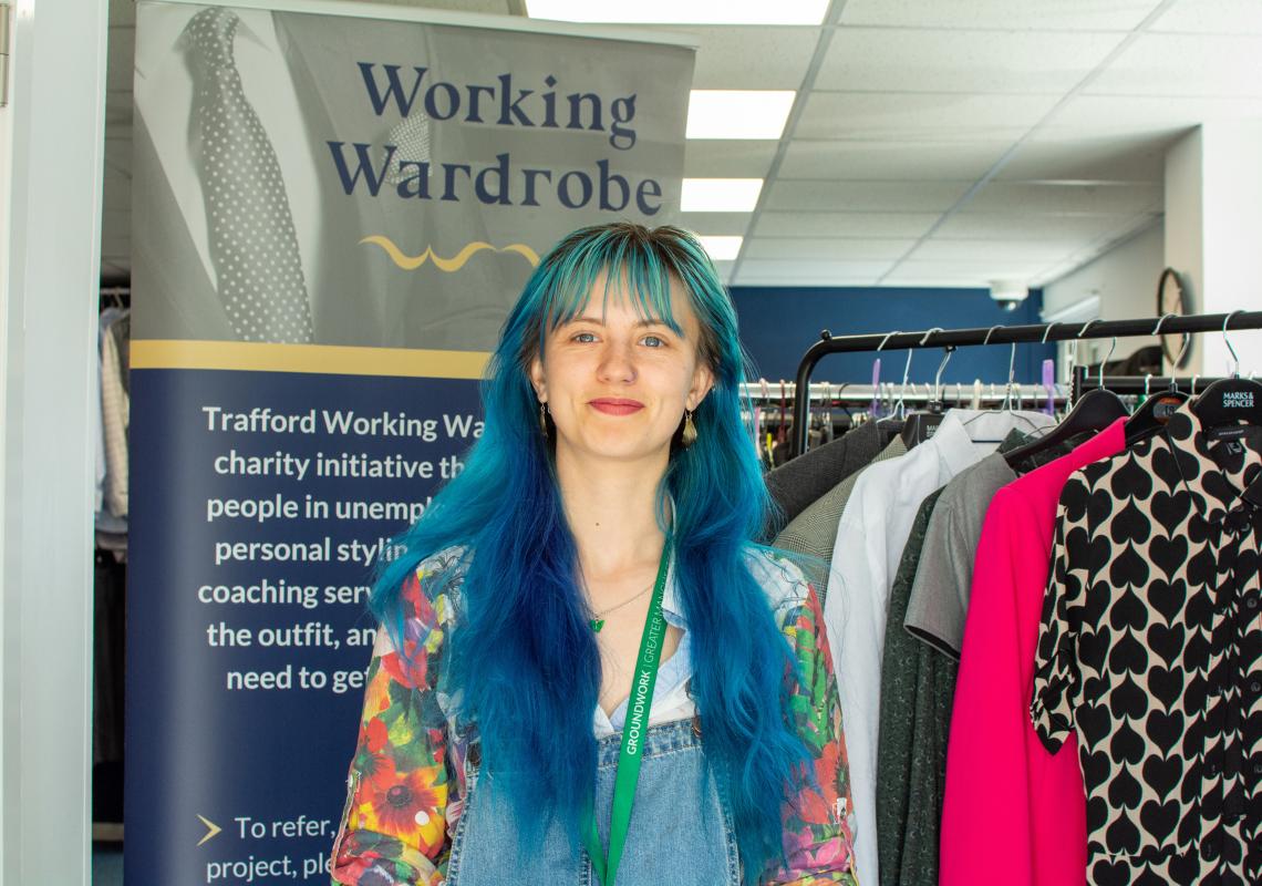 A young person (Leonie) smiling at the camera with Working Wardrobe in the background