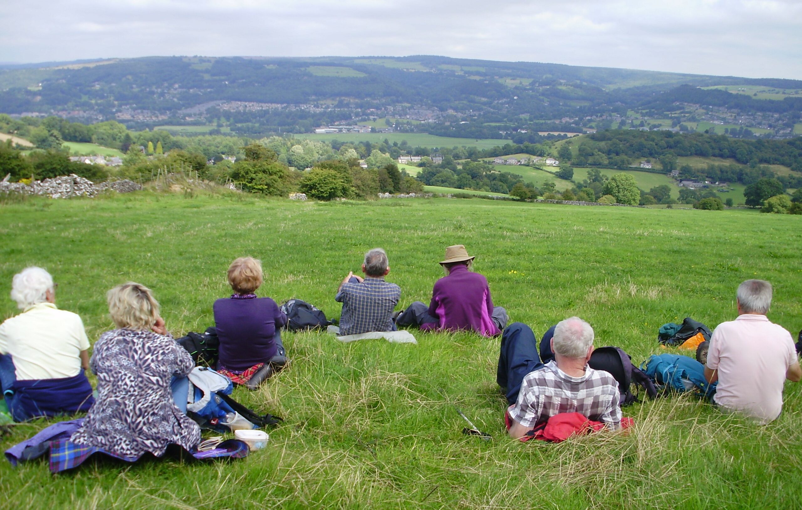 Group of people sitting down on grass with view of rolling hills