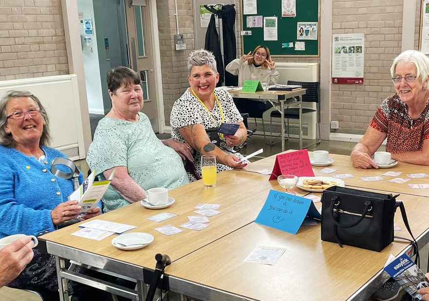 Women of varying ages sitting table, smiling