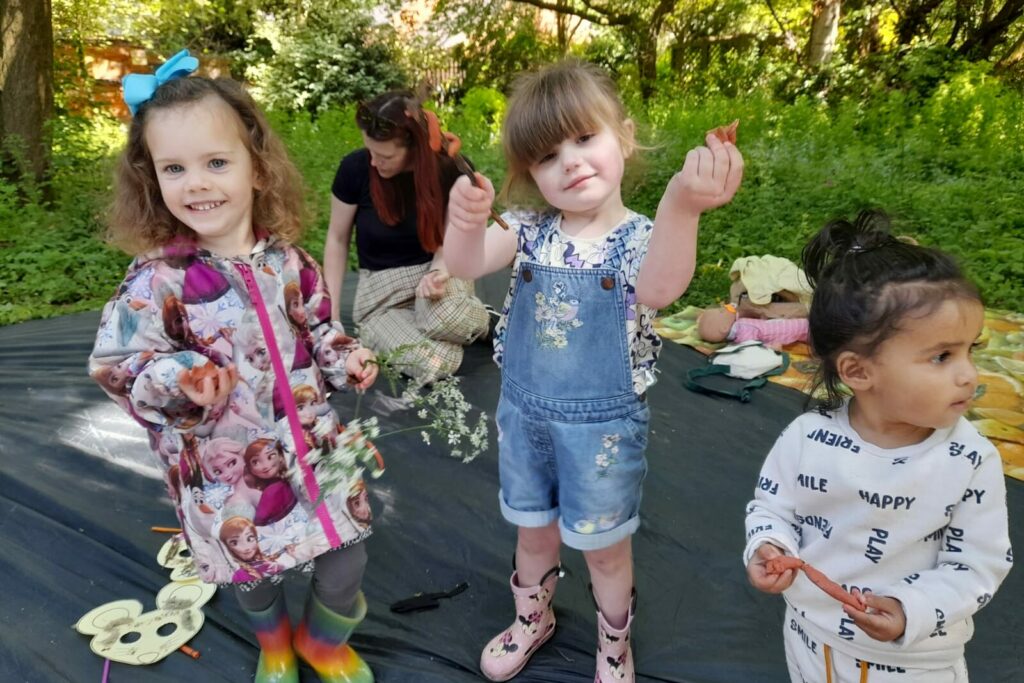 Three children holding clay animals in outdoors setting.