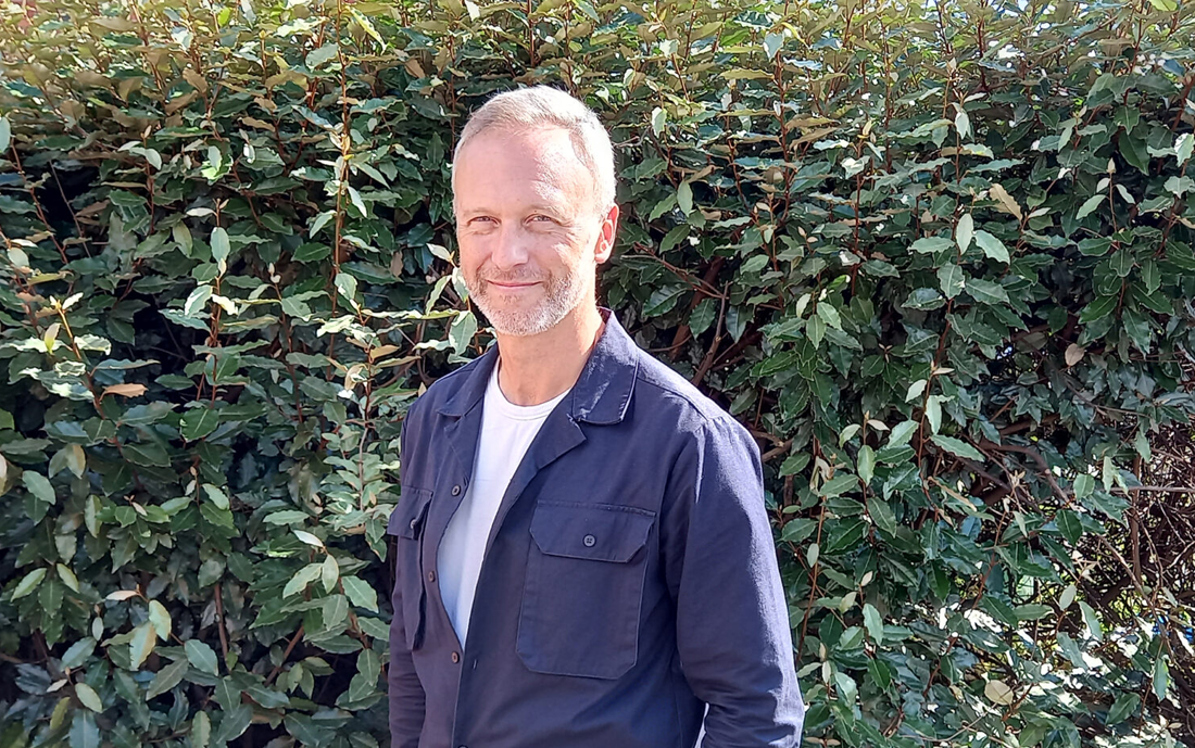 Gareth James, CEO (Interim) of Groundwork Five Counties. Man with short hair and dark blue shirt in front of shrubs.