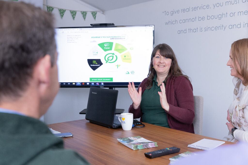 Three people in office setting round a table chatting