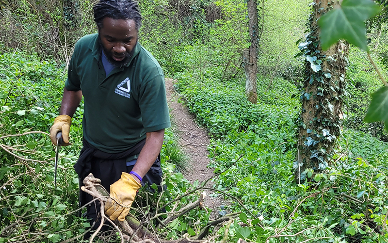 Man wearing green Groundwork shirt with yellow gloves, working in nature