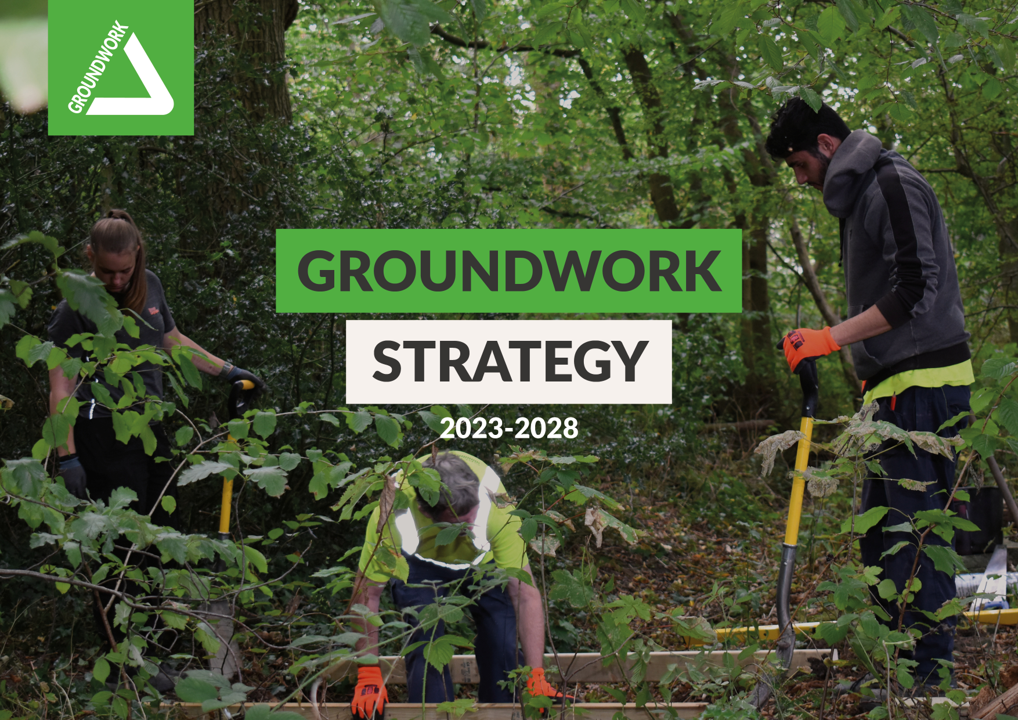 Image displaying volunteers working on a project in a wooded area.  The word 'groundwork strategy 2023 - 2028 are displayed across the front of the image with the groundwork logo top left.