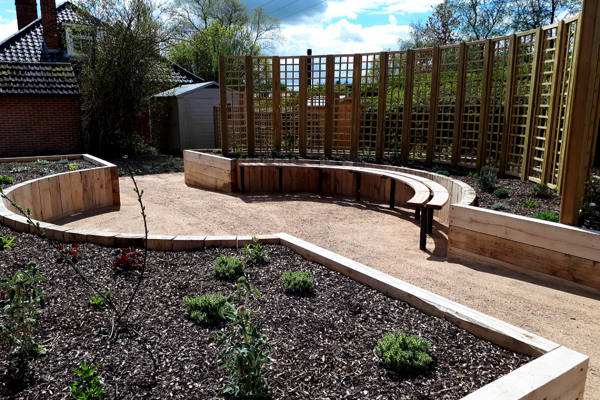 Newly built landscaped area with seating, raised beds and trelis