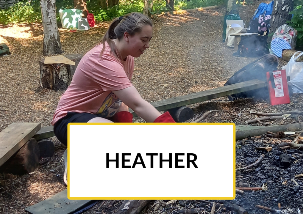 New to Nature Trainee Heather is tending to a fire in a woodland