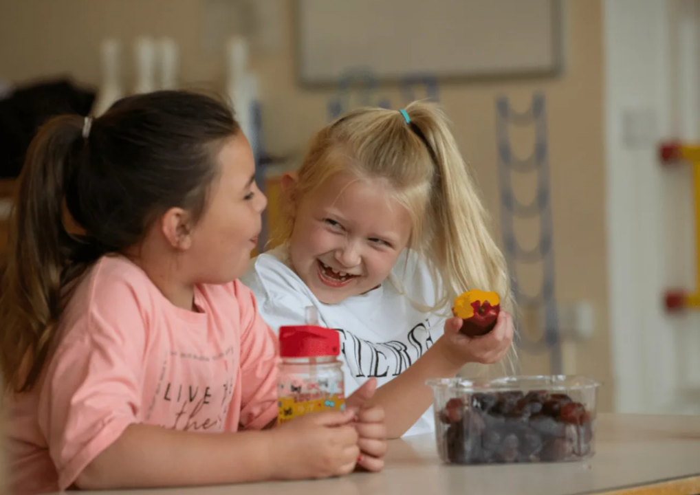 Two little girls eating fruit