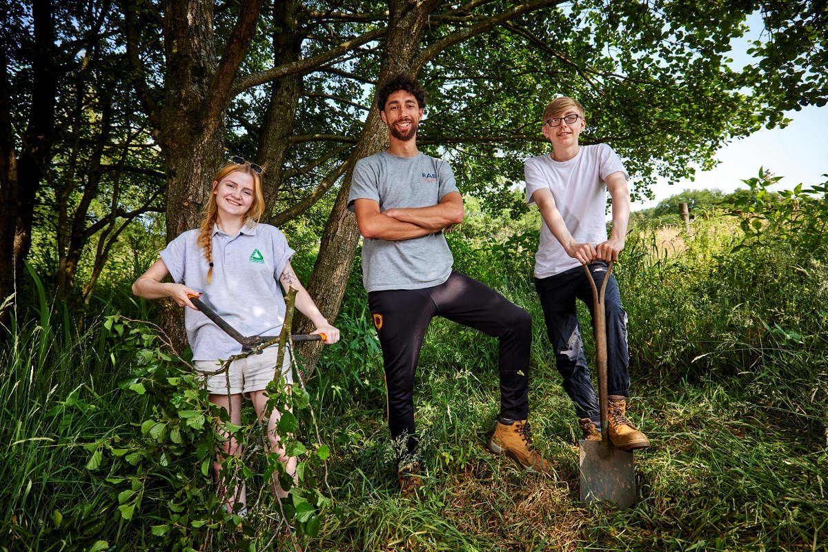 Young people smiling in the outdoors with spades