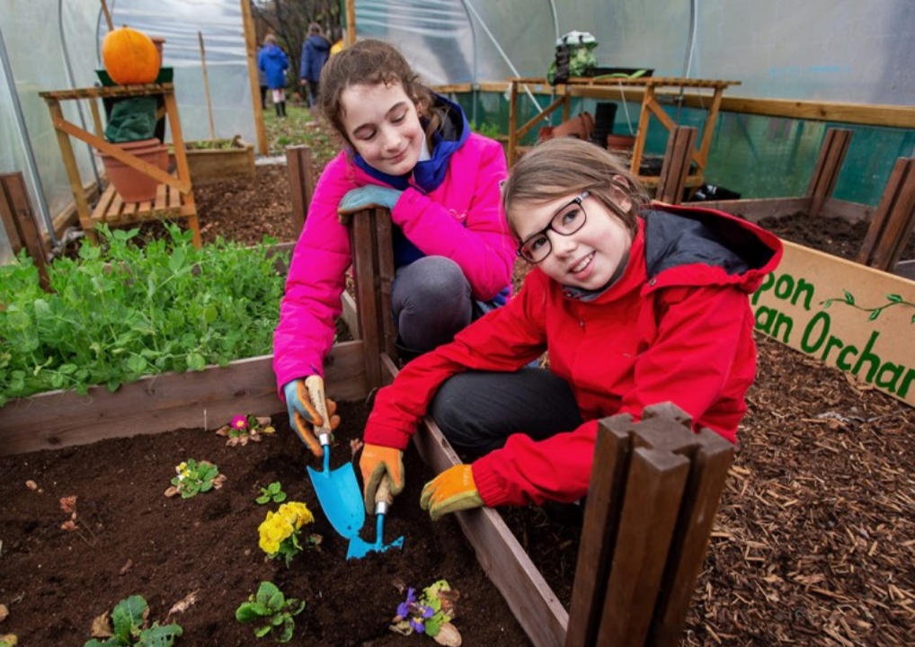 Image of 2 children gardening in a greenhouse