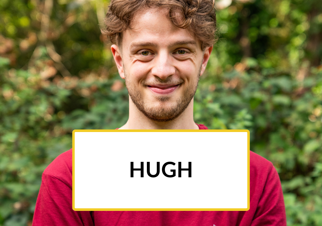 Trainee Hugh stands smiling in a park