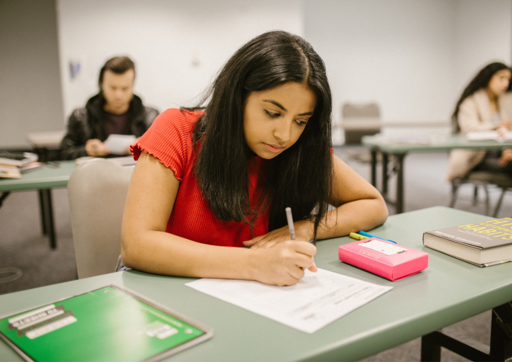 Photo of a girl sitting at a desk, writing on paper