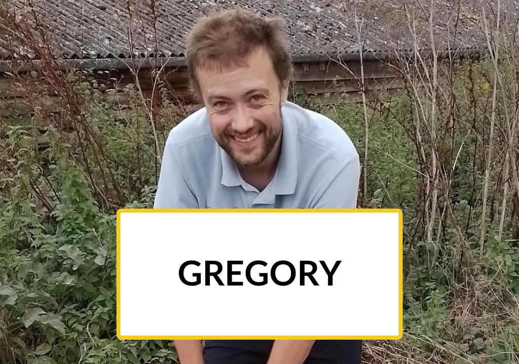 Trainee Gregory is mid-digging outside and smiling.