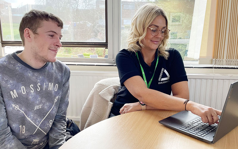 Young man and blonde woman looking at laptop in office.