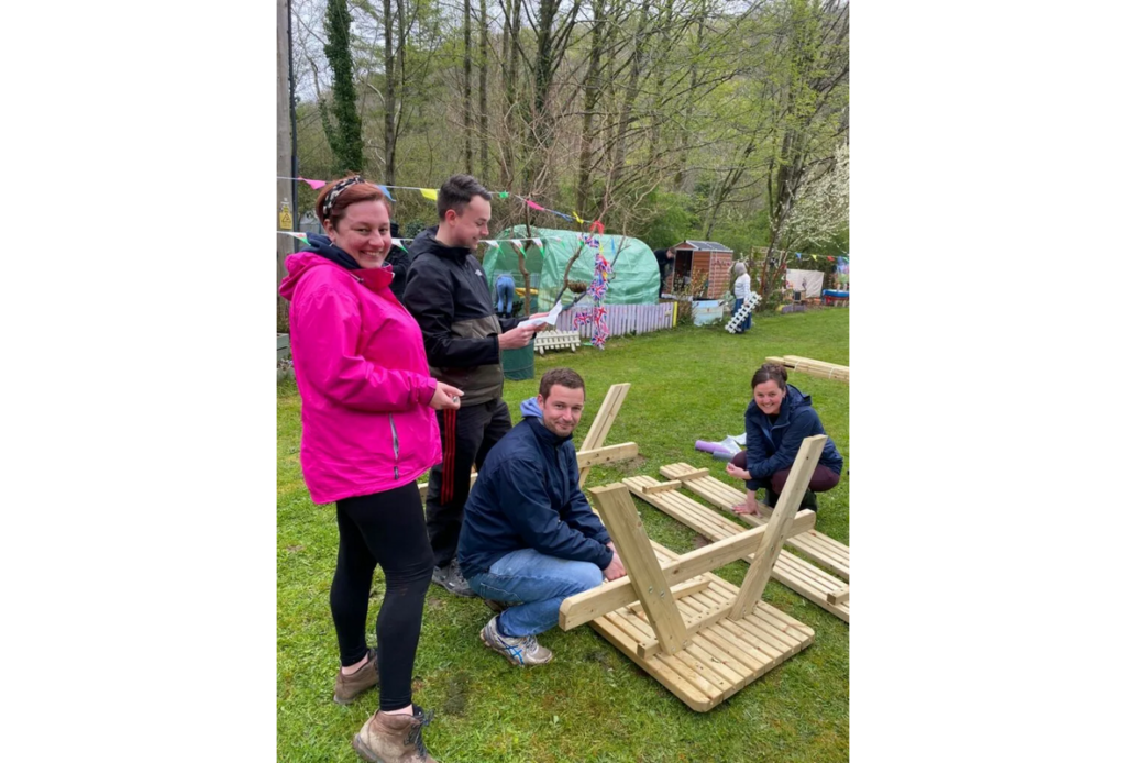 Four people in a park assembling a wooden bench 