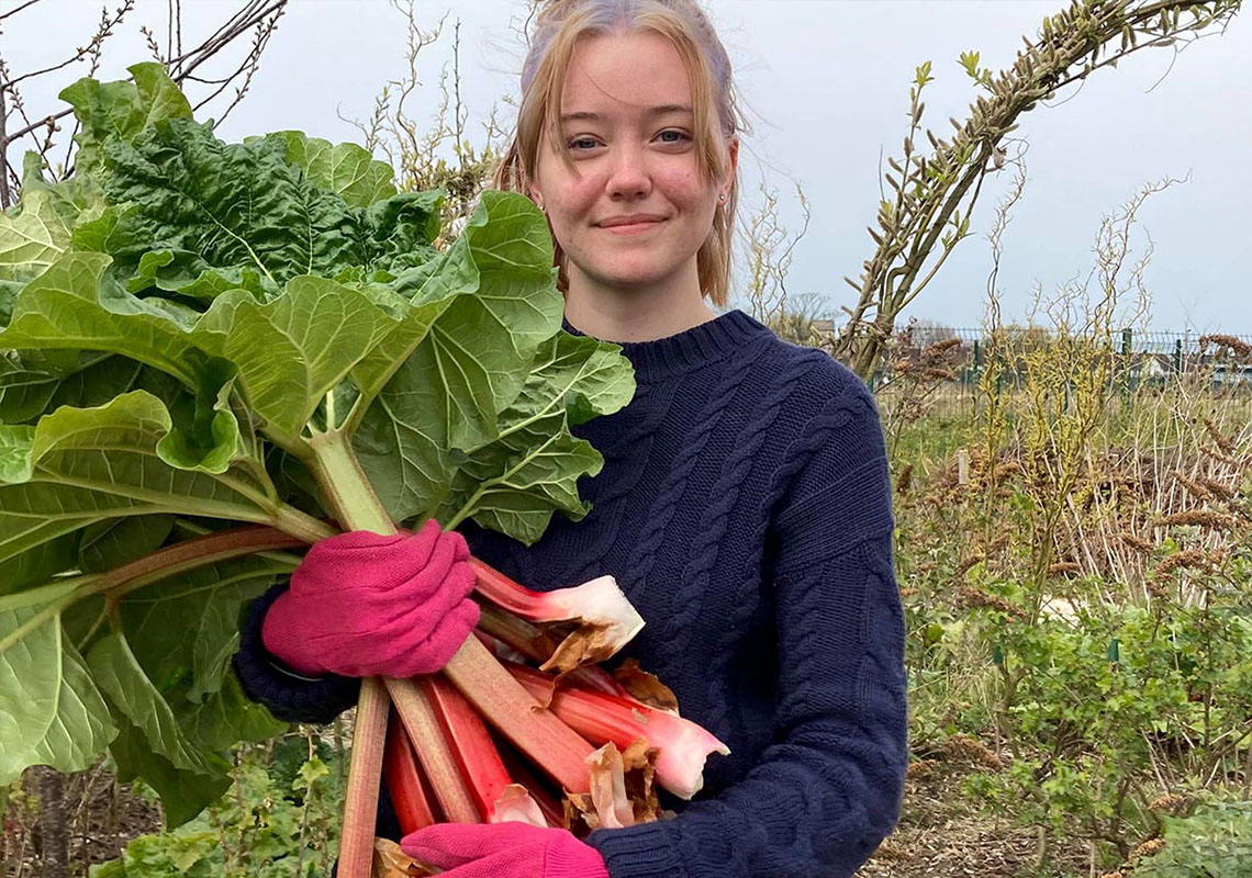 Volunteer holding harvest of crops at Grow Blackpool