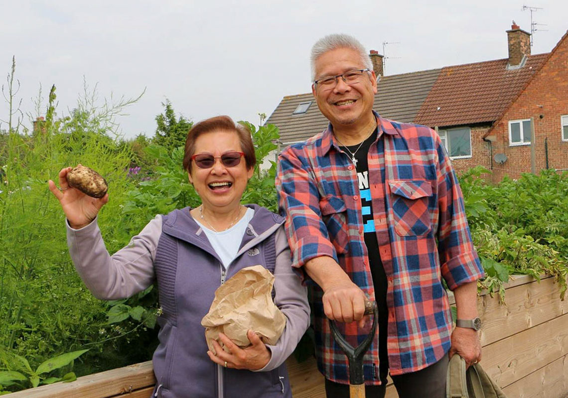 Two volunteers show off their harvest in a community garden
