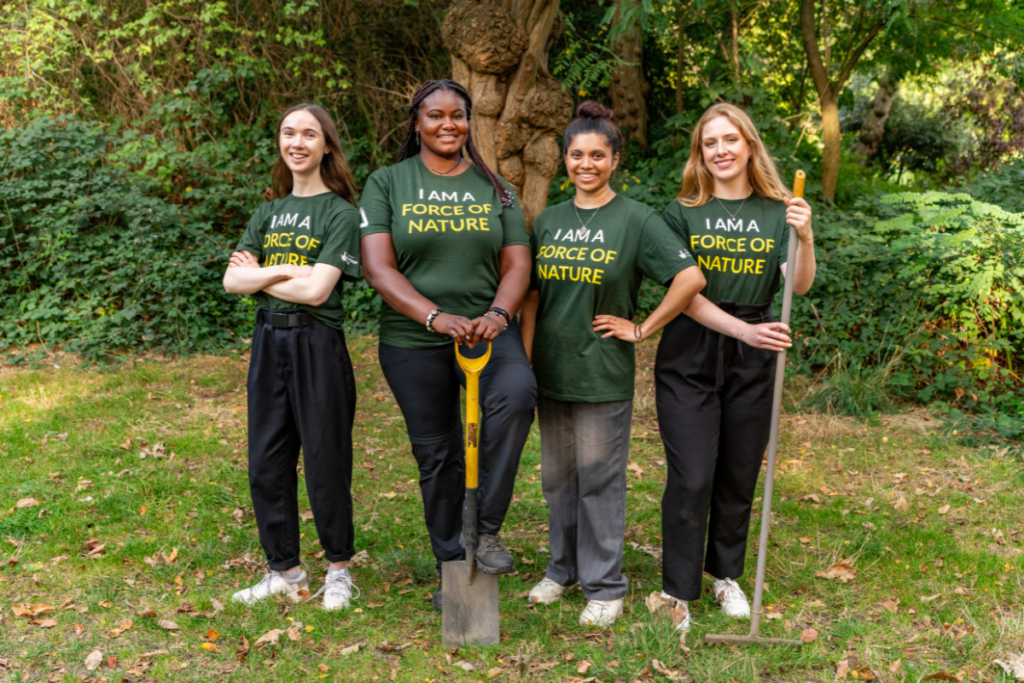 Photo of four young women holding gardening tools.