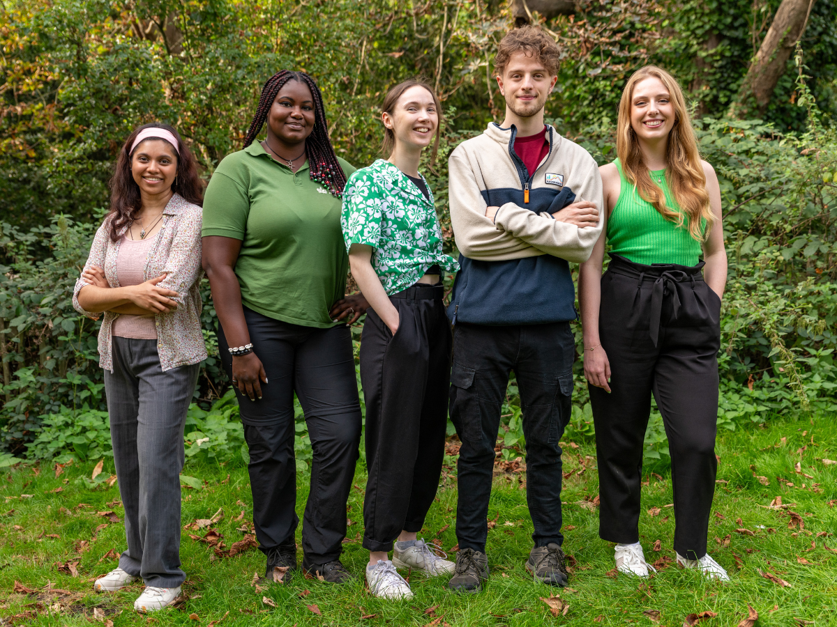 five young people smiling in an outside setting