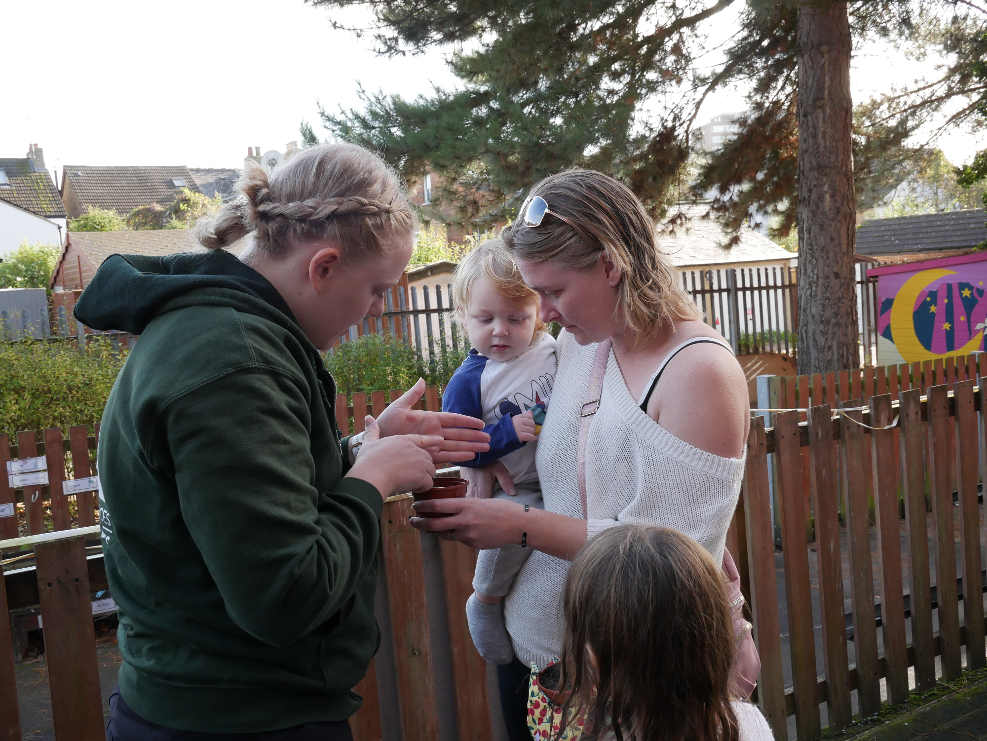 Showing a child in parent's arms seeds in a pot