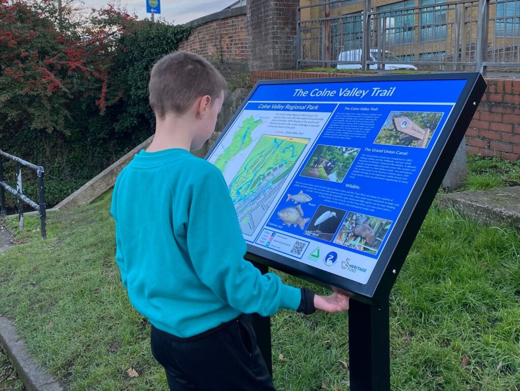 a young board look at an interpretation board in a park in south of england
