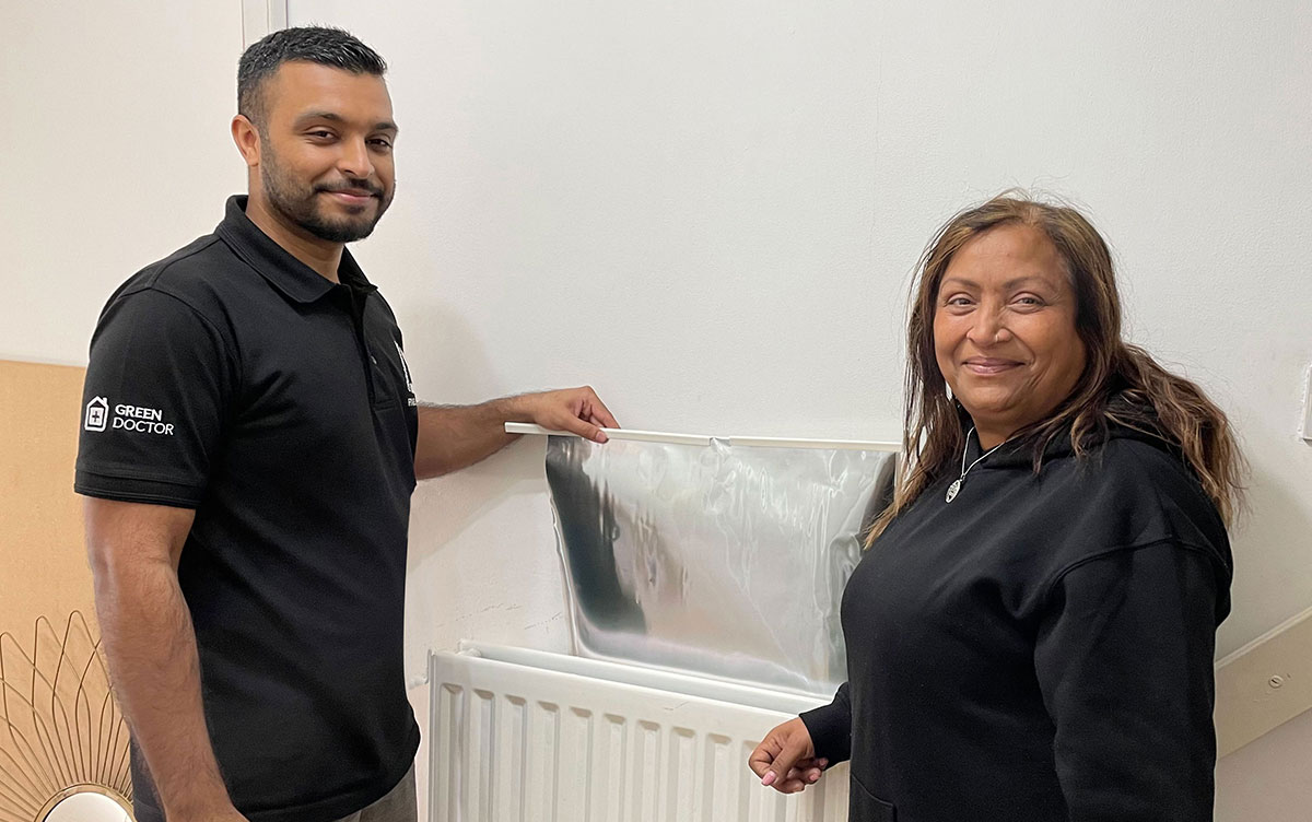 Man and woman with radiator panel smiling at camera.
