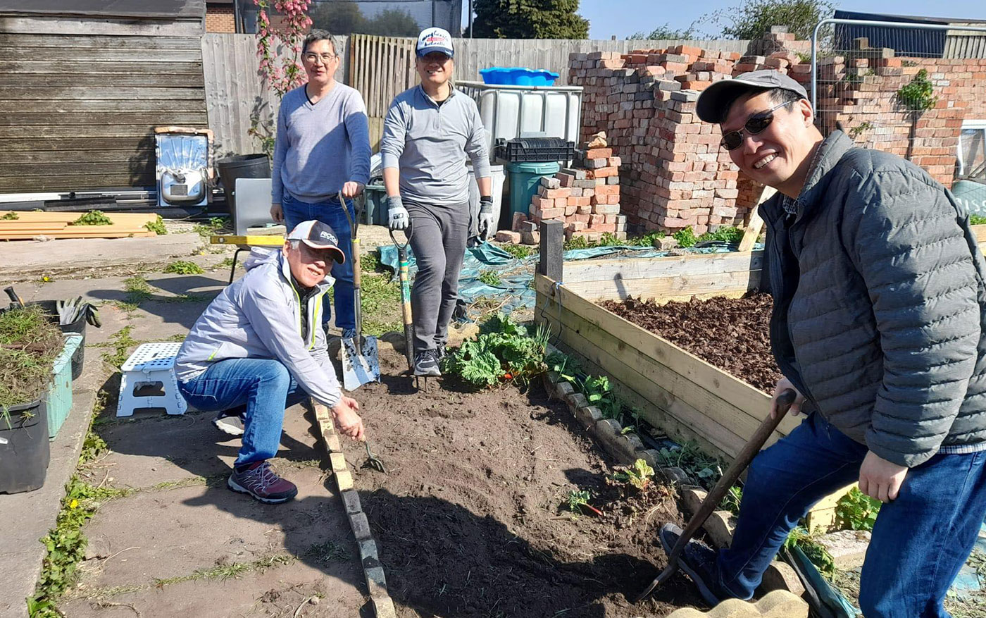 Group of people gardening, smiling at the camera