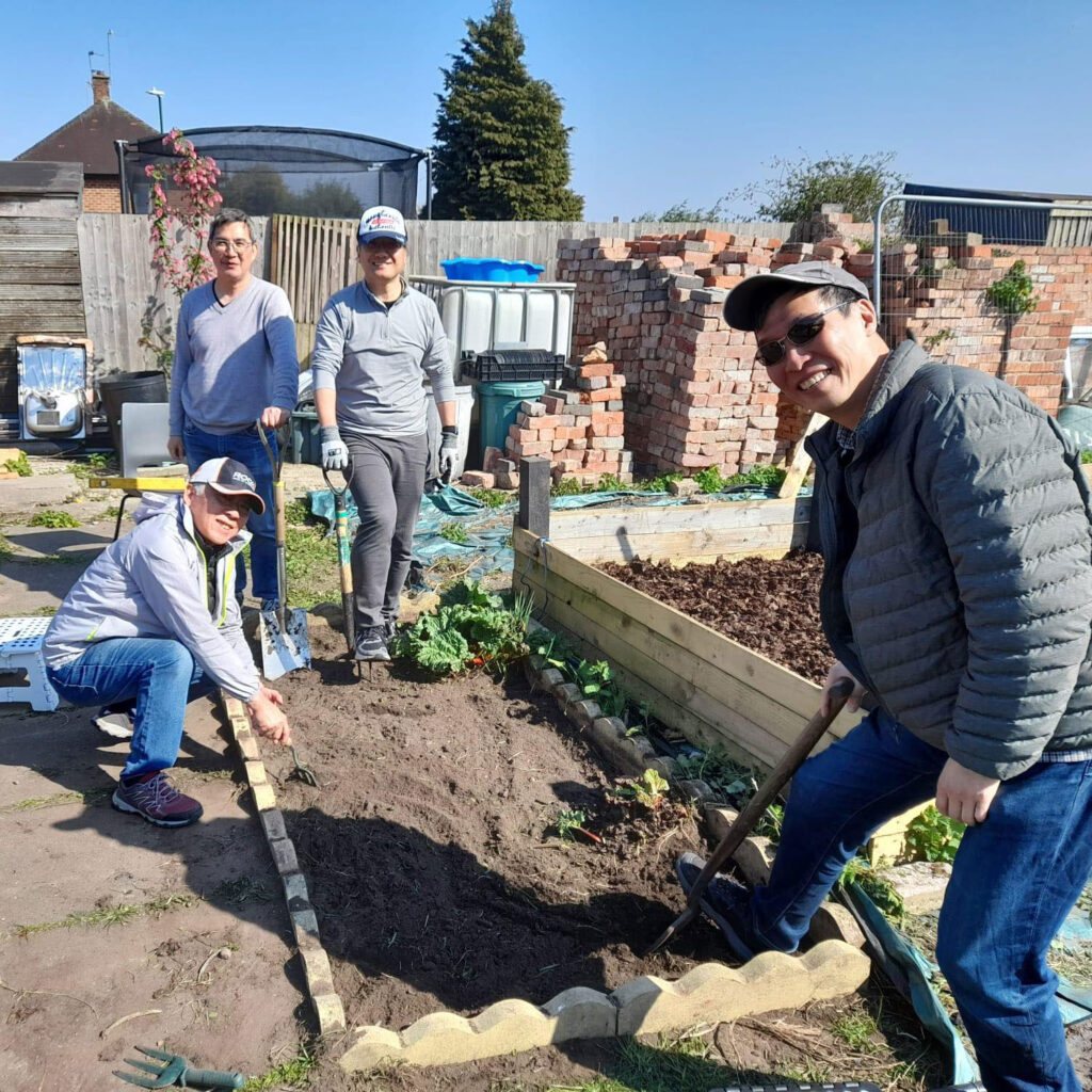 Group of people gardening, smiling at the camera