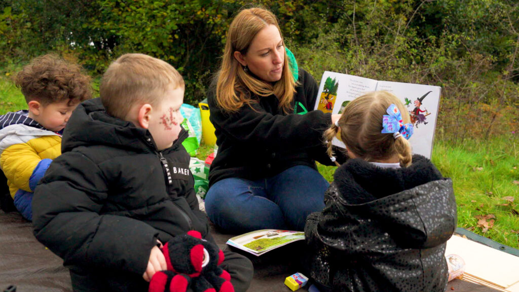 Support Wellies in the Woods: A Groundwork Project Officer reading a book to young children