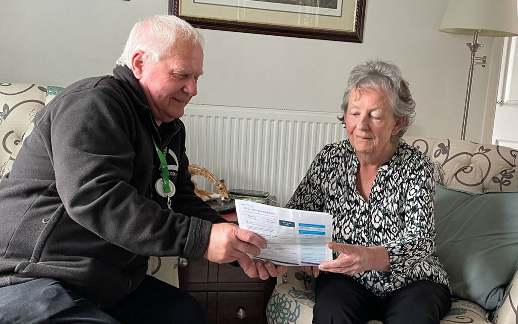 Man and woman looking at energy bills sitting on comfortable chairs.