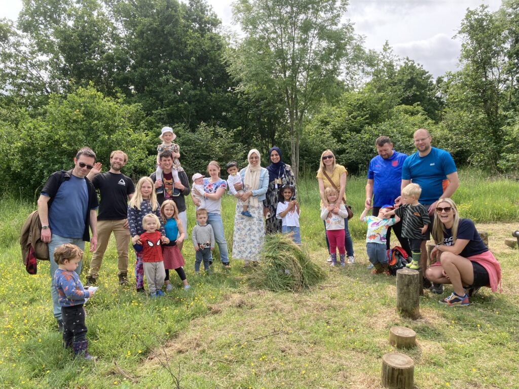 Group of adults and children in outdoor setting smiling at the camera.