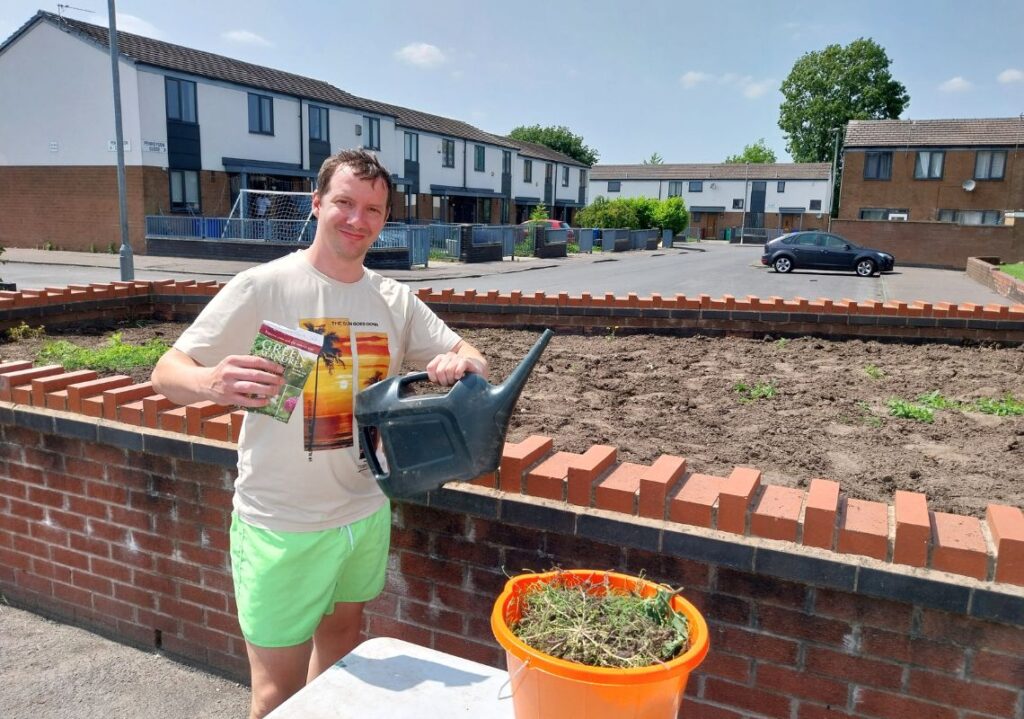 Resident with watering can after completing planting work with the Postcode Gardener