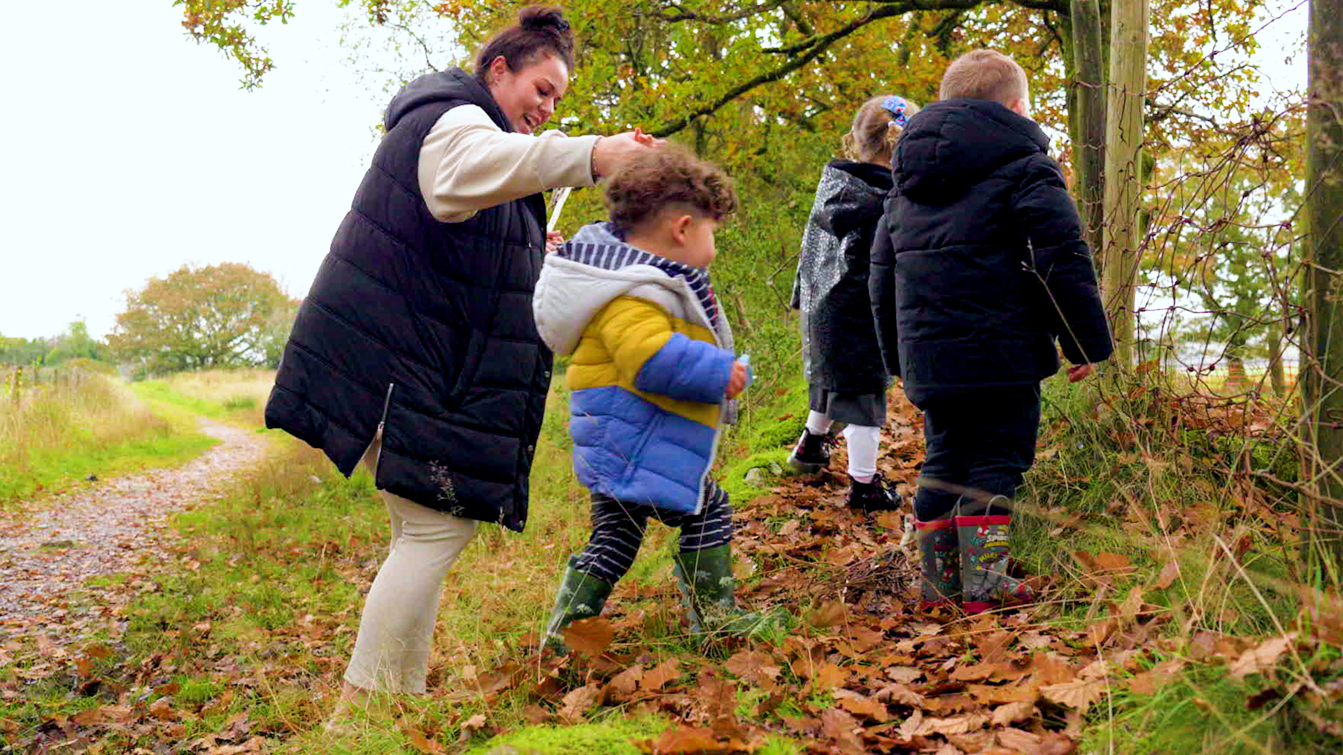 Photo of Woman holding a child's hand walking with children in the outdoors