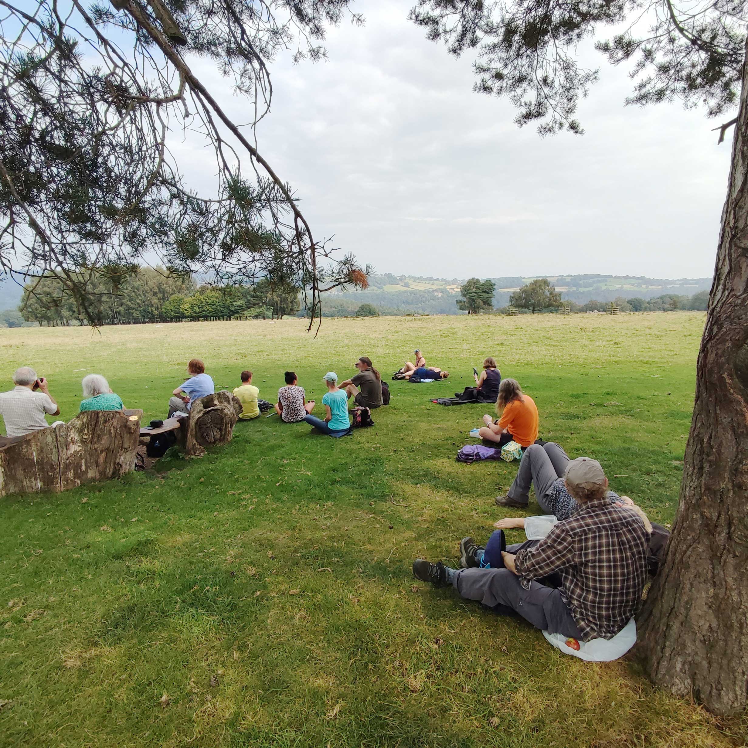 Group of people sitting on grass with wide view of hills