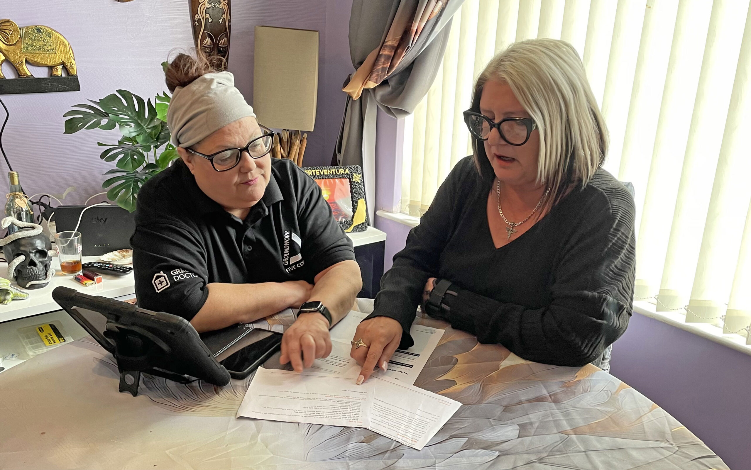 Two women sitting at table looking at papers.