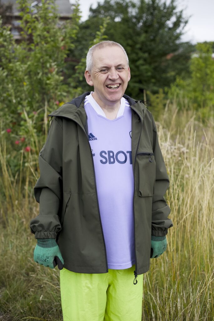 Photo of a man outside, smiling wearing green work gloves