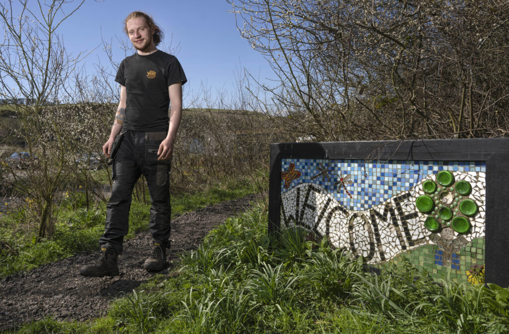 Photo of Ben outside walking beside a welcome sign