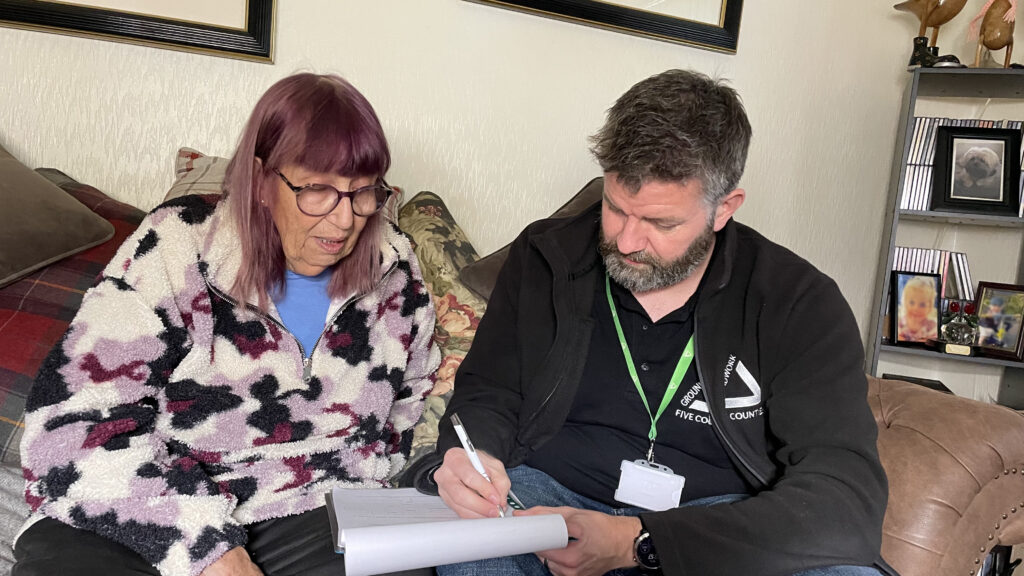 Woman and man filling out paperwork, sitting on a brown leather sofa.