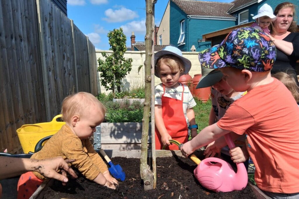 Children and parents planting seeds together ina garden