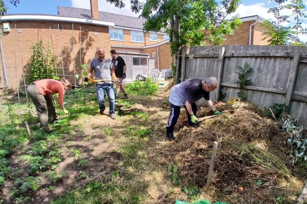 people digging and clearing a garden for a veg patch