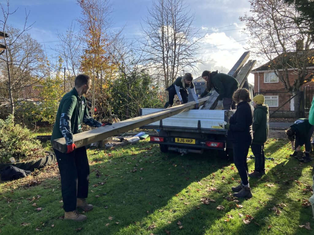 Groundwork staff unloading planks f wood from a tipper truck