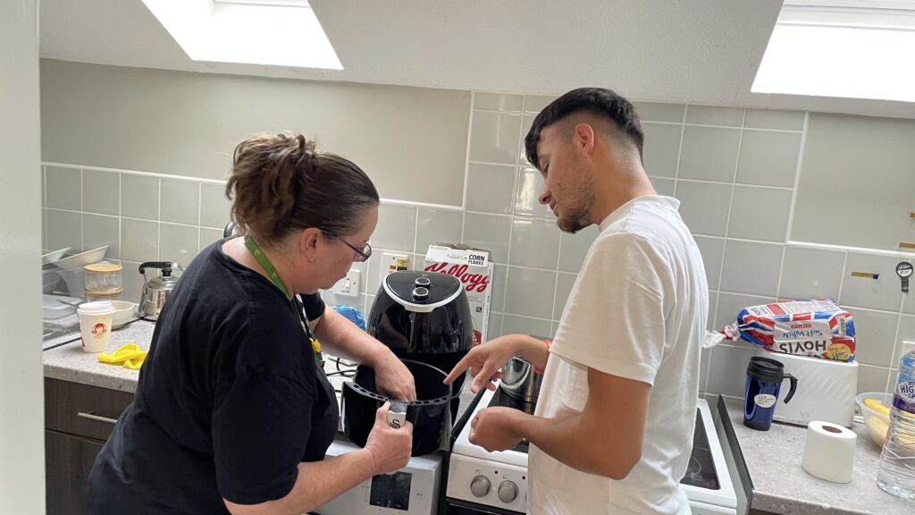 Man wearing white T-shirt and woman wearing black with an air fryer in kitchen.