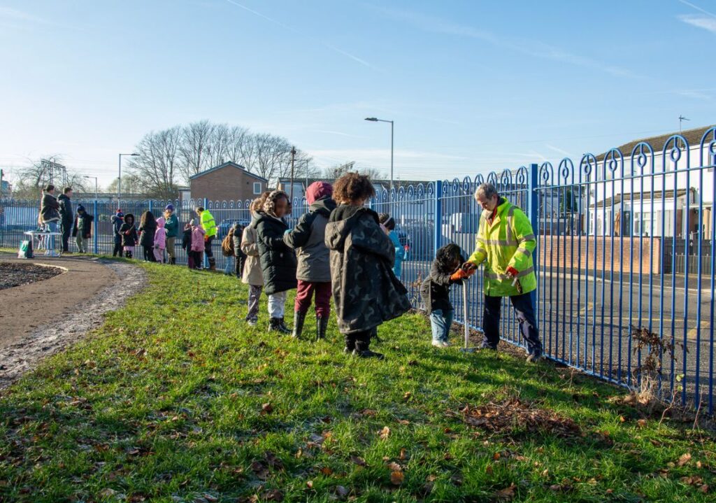 Pupils planting trees with the Postcode Gardener and Groundwork staff