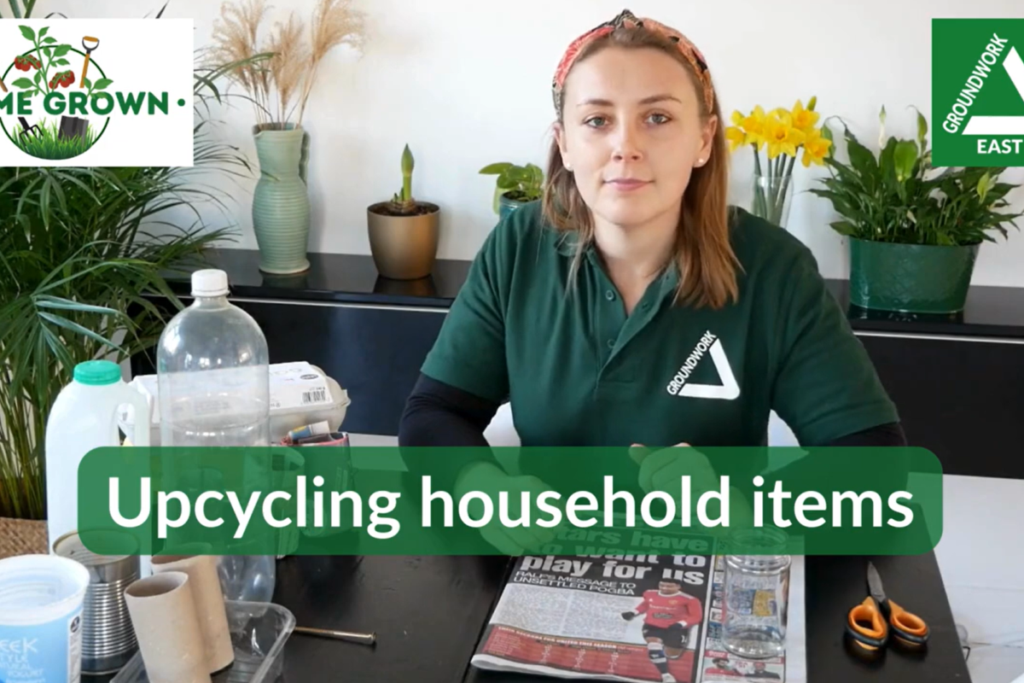Woman sitting at table to items to recycle household bottles and tins into plant pots